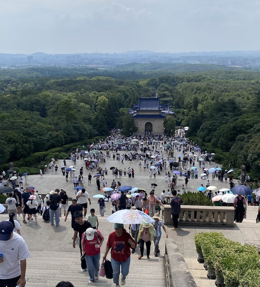 2026 年 8 月从中山陵祭堂平台俯瞰,台阶和广场上满是打伞的游客,我拍的实景